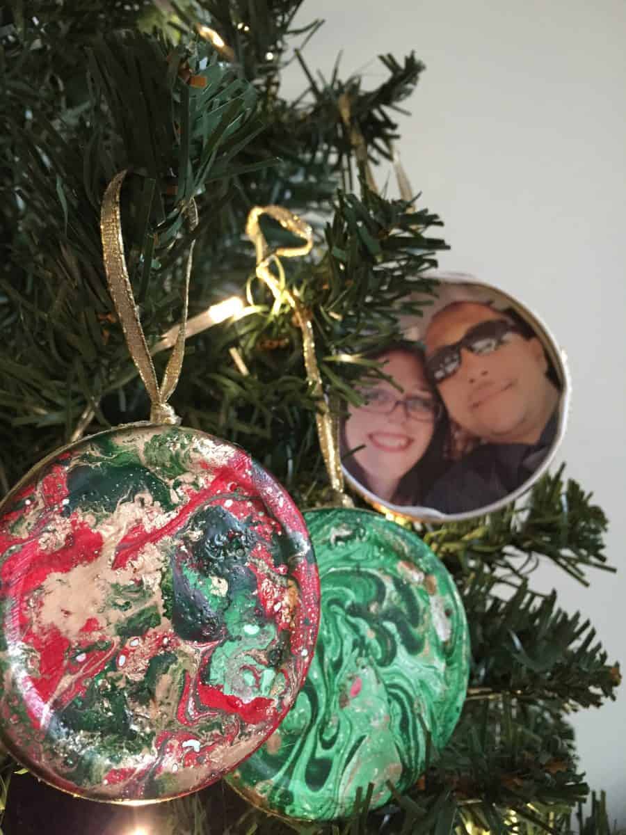 Create these DIY Marbled Picture Christmas Ornaments using upcycled jar lids. This craft is fun and easy to create for beautiful photo holding decoration.