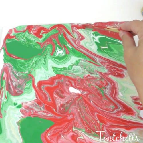 Create these beautiful poured Christmas rocks using acrylic paint and an inexpensive thickening agent. Pour painting is a fun process art technique that will mesmerize your kids.
