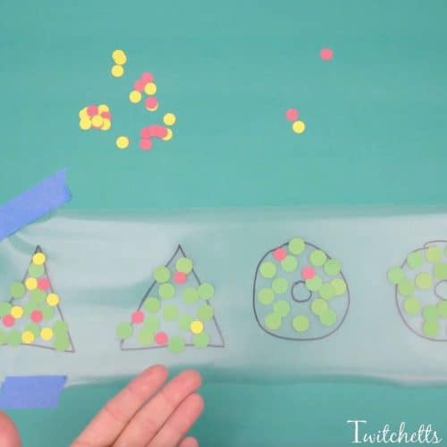 This fun fine motor Christmas ornament uses inexpensive construction paper to create a suncatcher that can be given as a gift or hung on your tree.