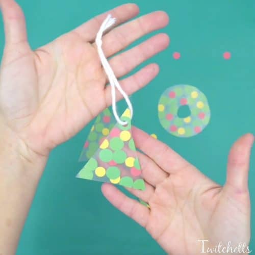This fun fine motor Christmas ornament uses inexpensive construction paper to create a suncatcher that can be given as a gift or hung on your tree.
