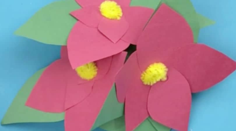 Create this paper poinsettia craft that kids will love to see decorating their house or classroom this year. It's a perfect poinsettia decoration for houses with pets and small children. #paperpoinsettia #poinsettiacraft #craftforkids #christmascraft #poinsettiadecoration #christmaspapercraft #constructionpapercraftsforkids #classroomcraft #twitchetts