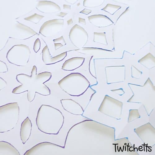 Make a six-sided snowflake paper craft with inked edges. They are perfect for winter decorating, classroom craft projects, or creating winter cards. The inked edges make the white paper pop! #snowflake #sixsided #papersnowflake #howtocutasnowflake #wintercraft #classroomcraft #classroomdecor #winterdecor #twitchetts