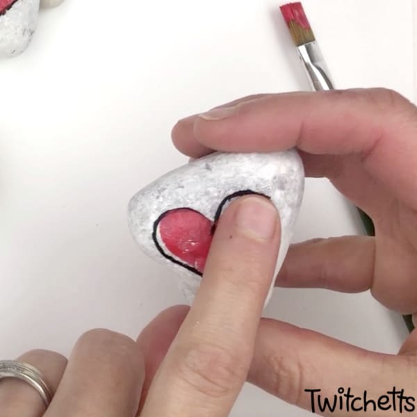 Create easy and fun heart and cross rocks with this simple tutorial. Use fingerprints to create this cross rock painting idea! #twitchetts
