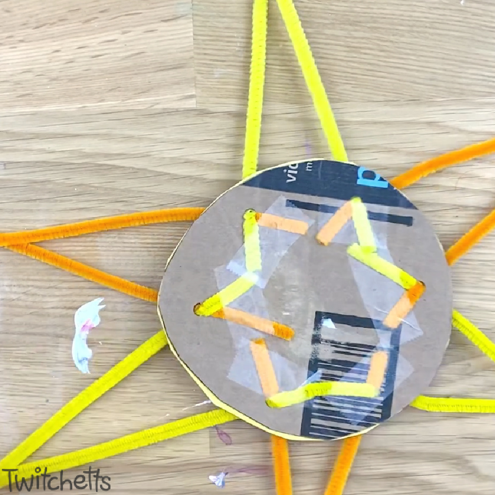 In process image of a cardboard and pipe cleaner sun craft for preschoolers.