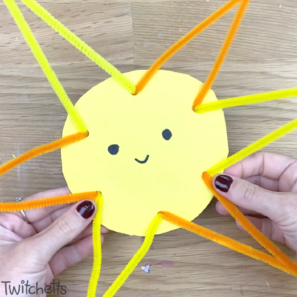In process image of a cardboard and pipe cleaner sun craft for preschoolers.